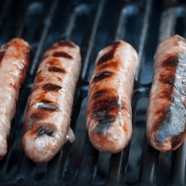 Brats cooking on a grill