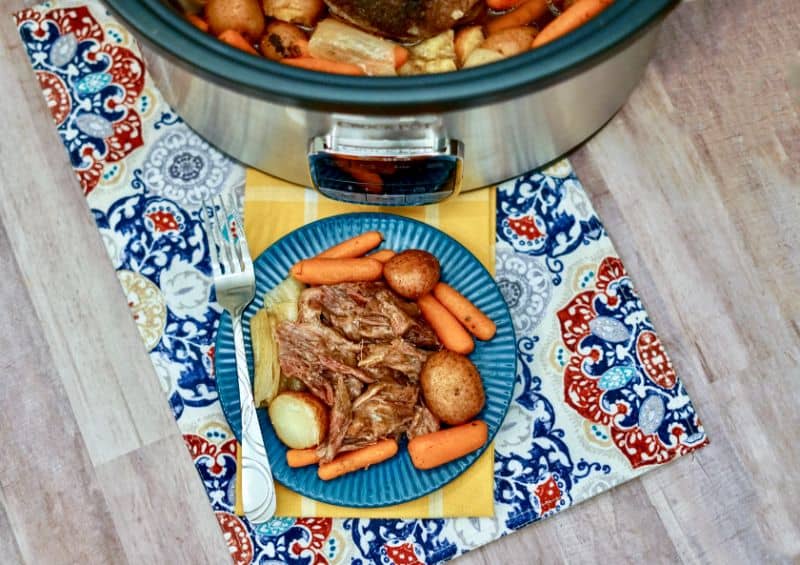 plated roast with veggies in front of the crock pot