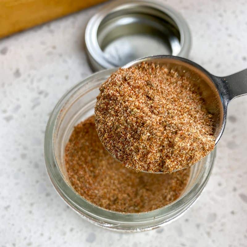 homemade cajun seasoning being scooped out of a glass jar