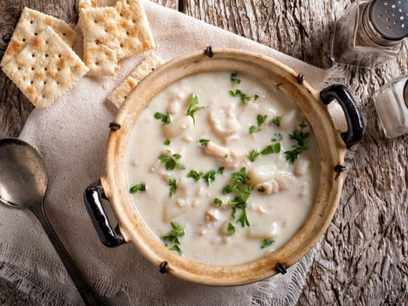 clam chowder in a bowl with crackers on the side