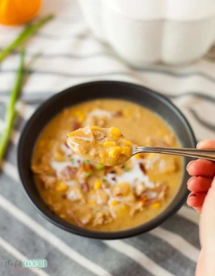 chicken corn chowder in a black bowl with spoon of chowder in foreground