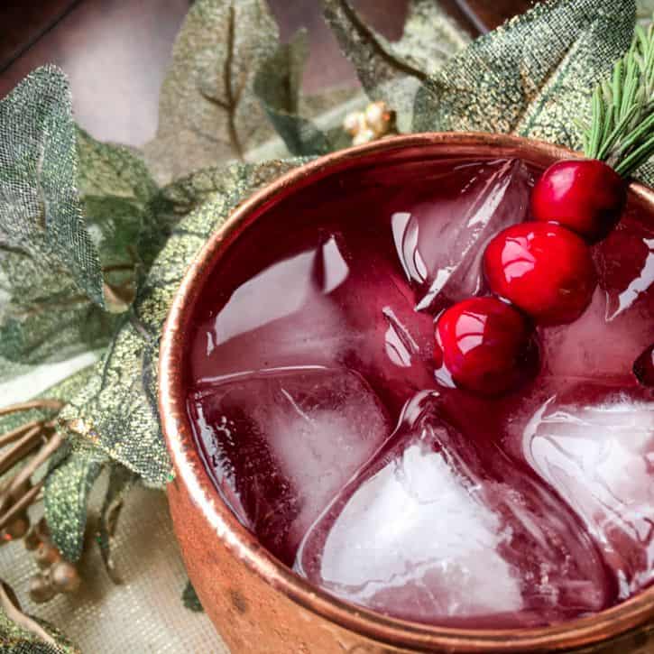 cranberry mule in copper cup with green leaves in the background