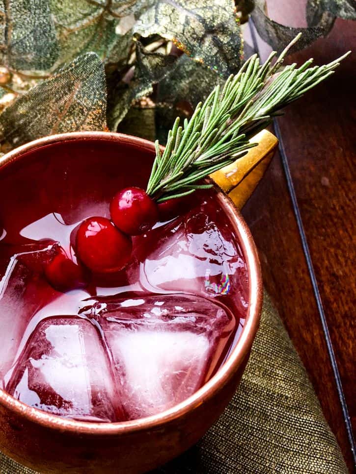 cranberry mule in copper cup with focus on the cranberry-rosemary sprig