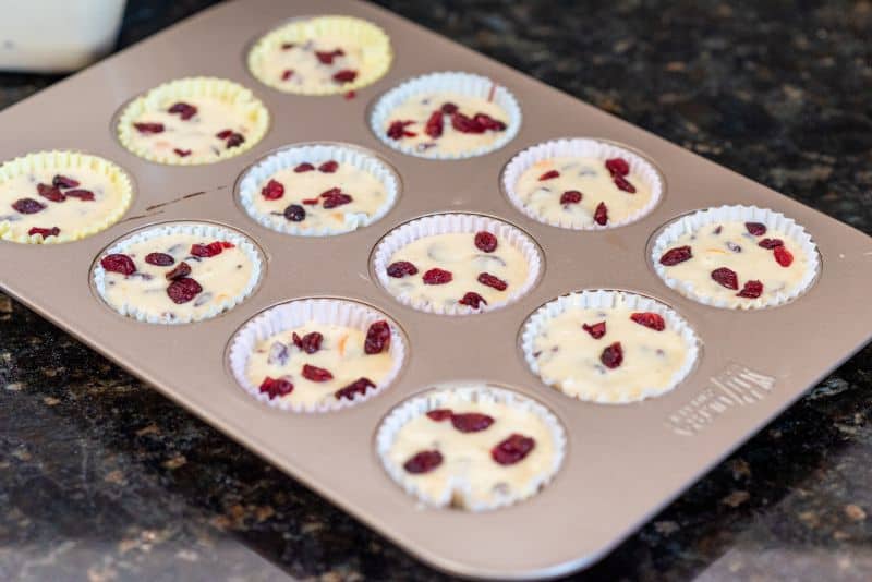 unbaked muffins topped with dried cranberries