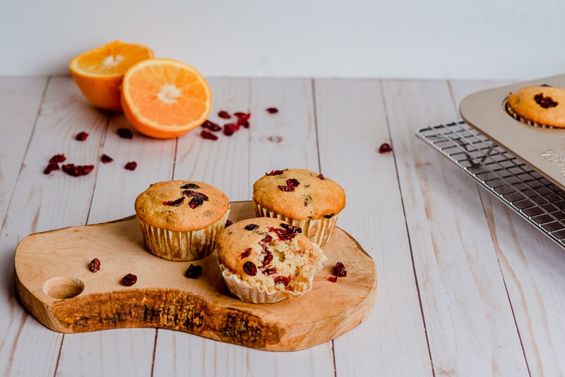 moist cranberry orange muffins on wood slice