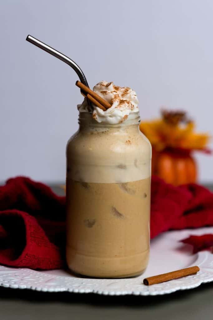 pumpkin latte vegan garnished with vegan whipped cream and cinnamon sticks