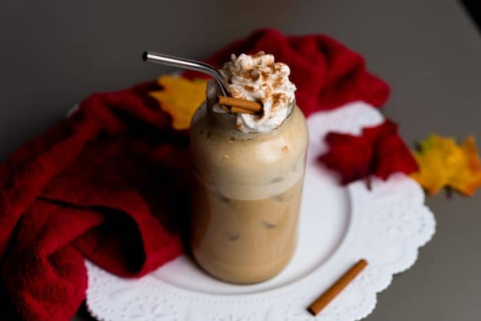 vegan pumpkin latte in tall glass on white serving platter with red napkin