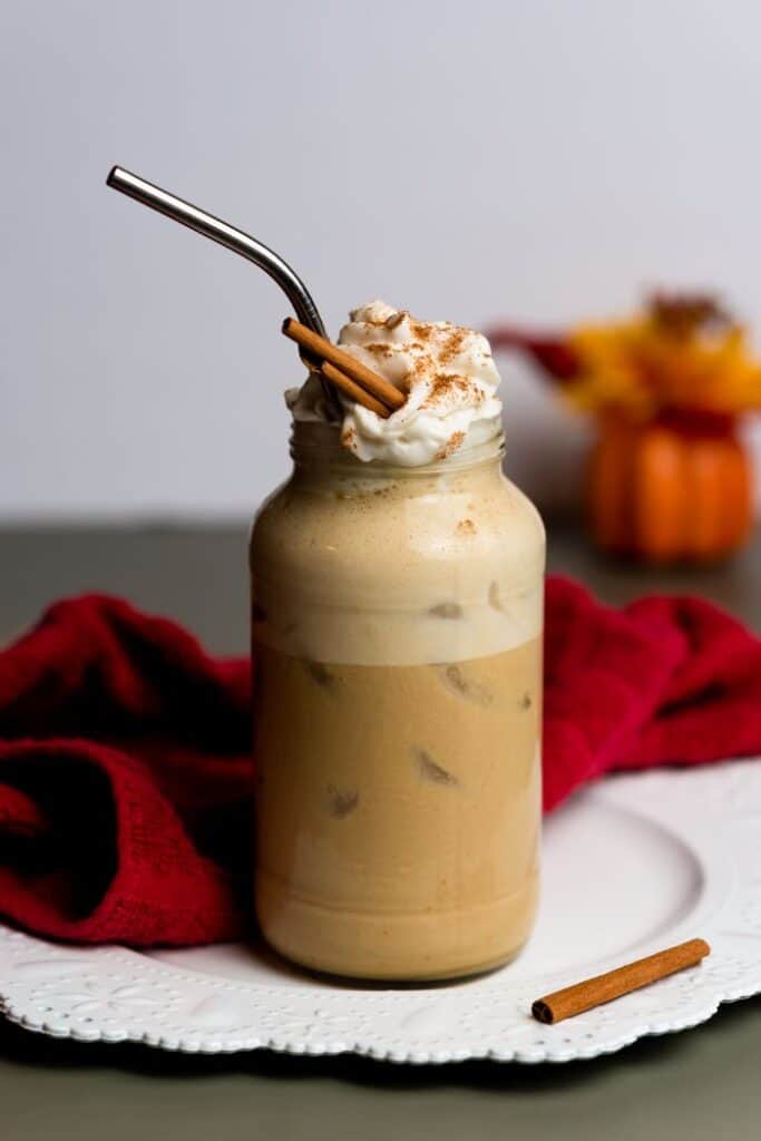 easy vegan pumpkin latte served over ice in tall mason jar type glass