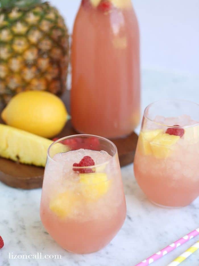 pink party punch in glasses with raspberries and pineapple chunks