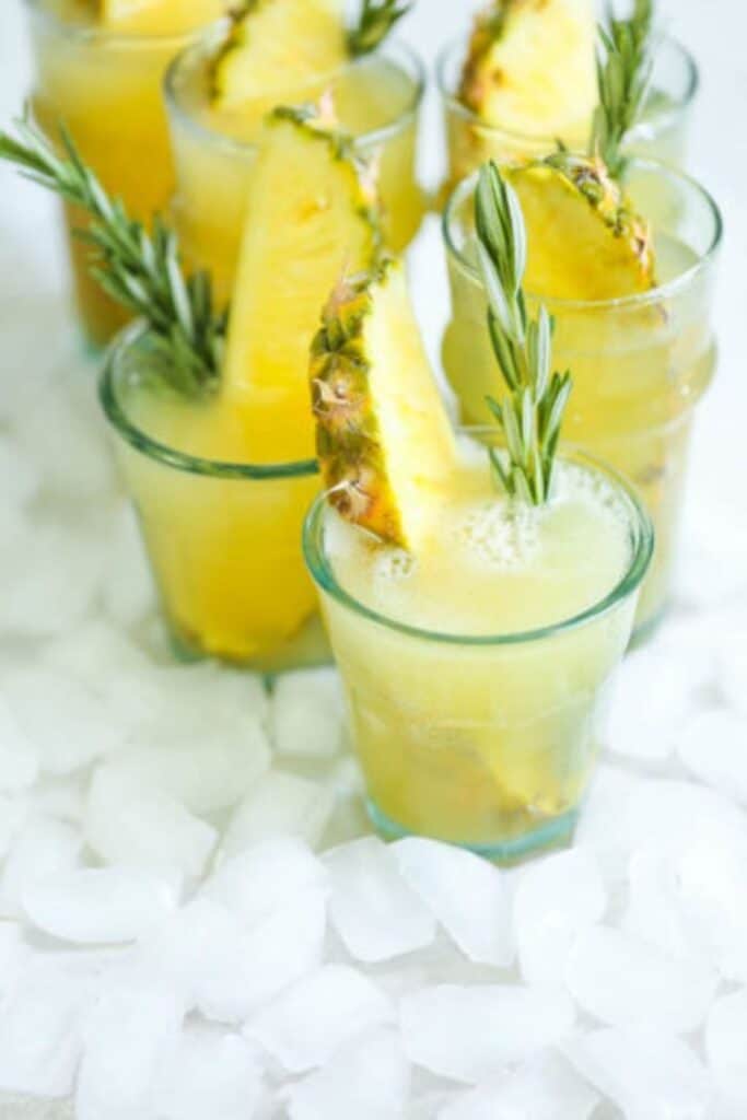 pineapple prosecco punch in glasses with pineapple wedges and rosemary sprigs