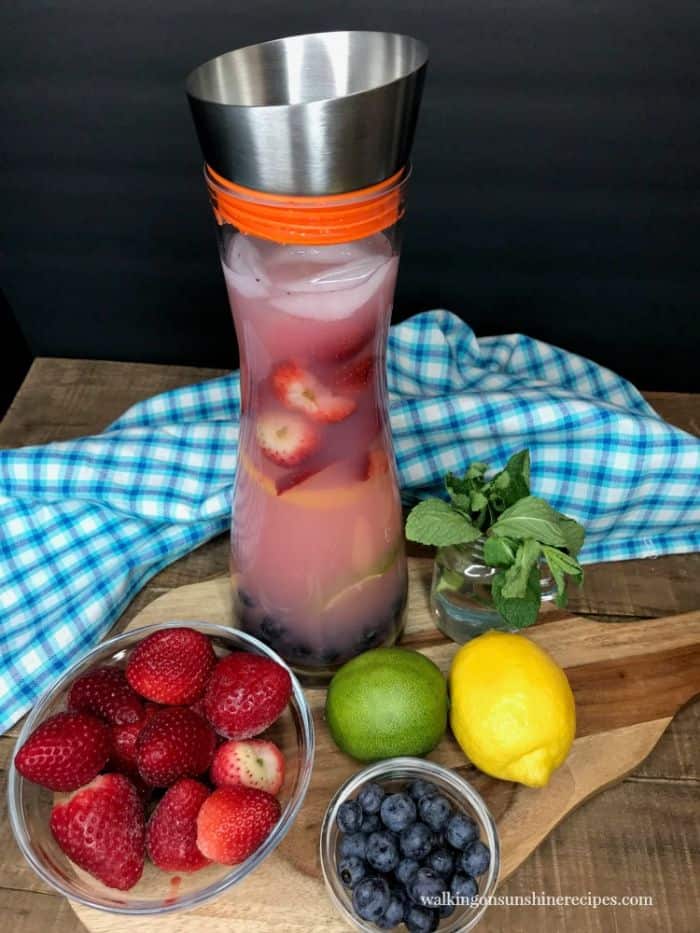 strawberry lemonade punch in a water infuser with berries and fruit