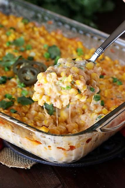 cheesy fiesta corn casserole in clear baking pan with some scooped out