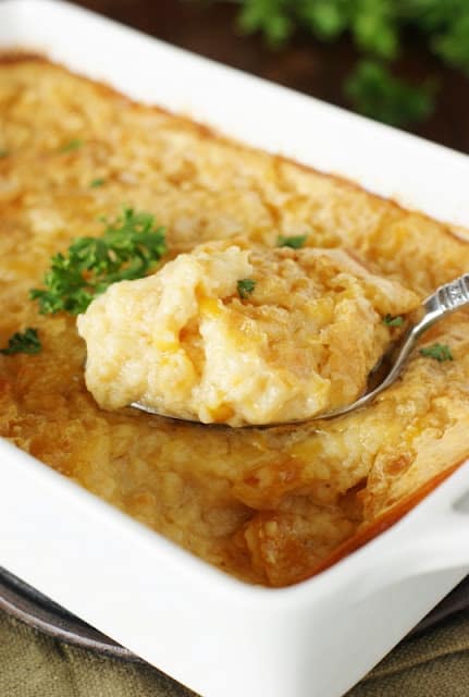 corn pudding in white baking dish with spoon scooping some out