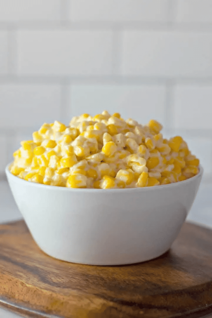 cream cheese corn casserole in a white bowl on cutting board