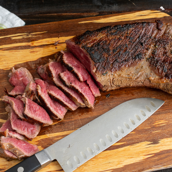 Rare slices of tri-tip steak on a bamboo cutting board