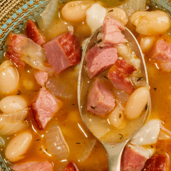 Close up of ham and bean soup with a spoon on top.