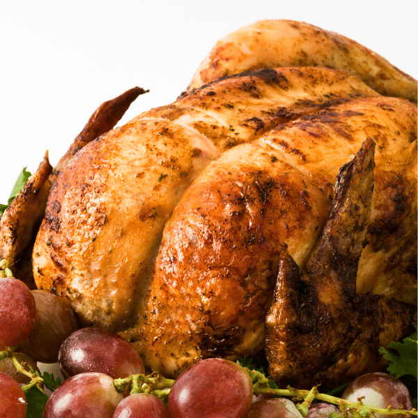 Garnished baked turkey plated with grapes as ganished.
