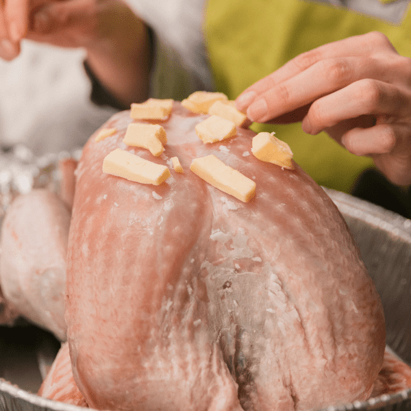 Mother putting butter on a turkey.