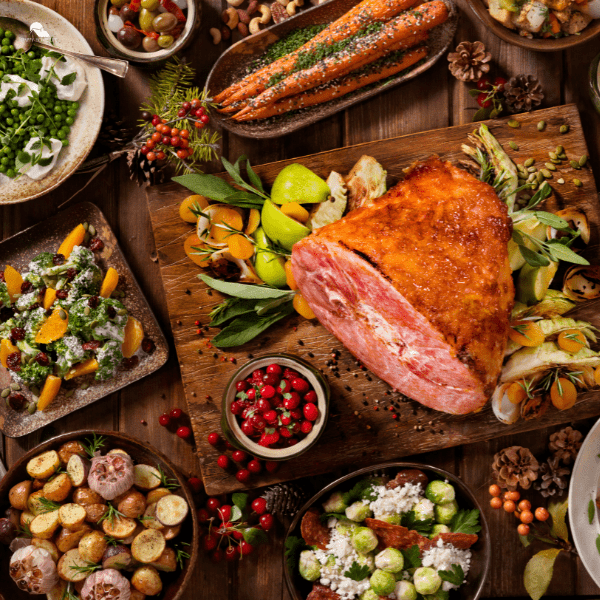 How Many Sides Should You Have for Christmas Dinner - Mapple ham surrounded with sides of potatoes, vegetables salads and carrots.