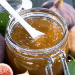 fig jam in a jar with a spoon inside.