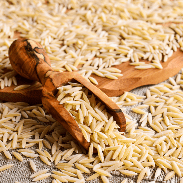 pasta orzo in the form of rice grainds in a wooden scoop.