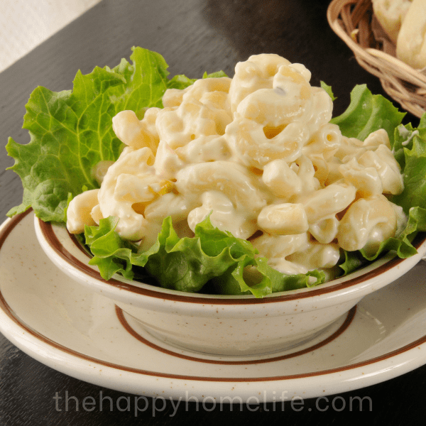 A bowl of macaroni salad in a small plate with dinner rolls