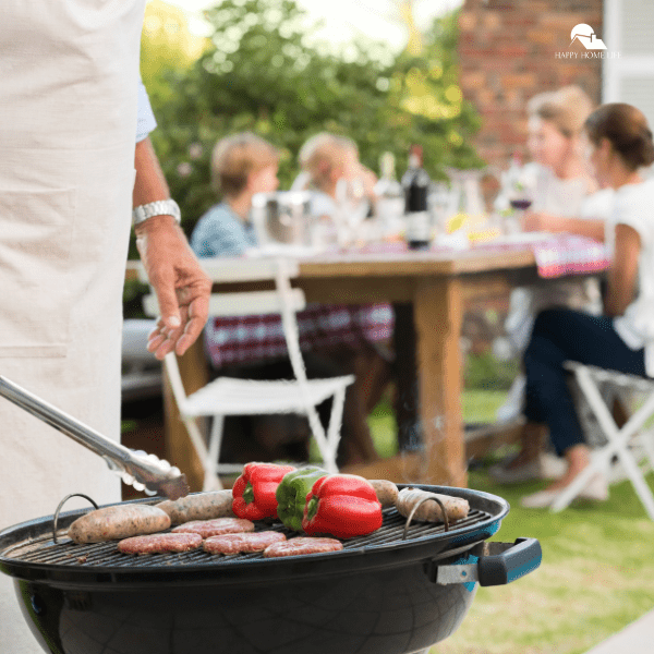 close up hand of a senior man barbecuing in the garden with guests in the background