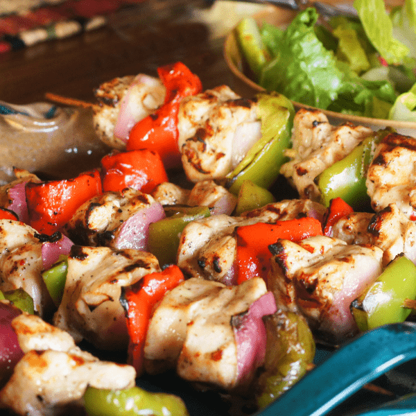 Close up of shish kabob with fresh green salad.