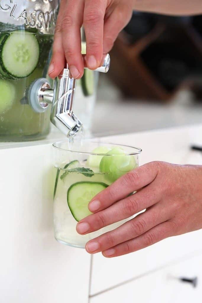 hands on drink dispenser with cucumber vodka cocktail
