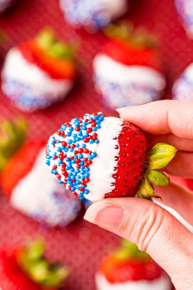 fingers holding patriotic dipped strawberries