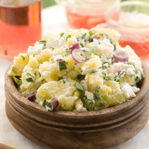 Potato salad in a brown bowl served outdoors.