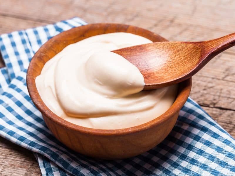 sour cream in wooden bowl with wooden spoon