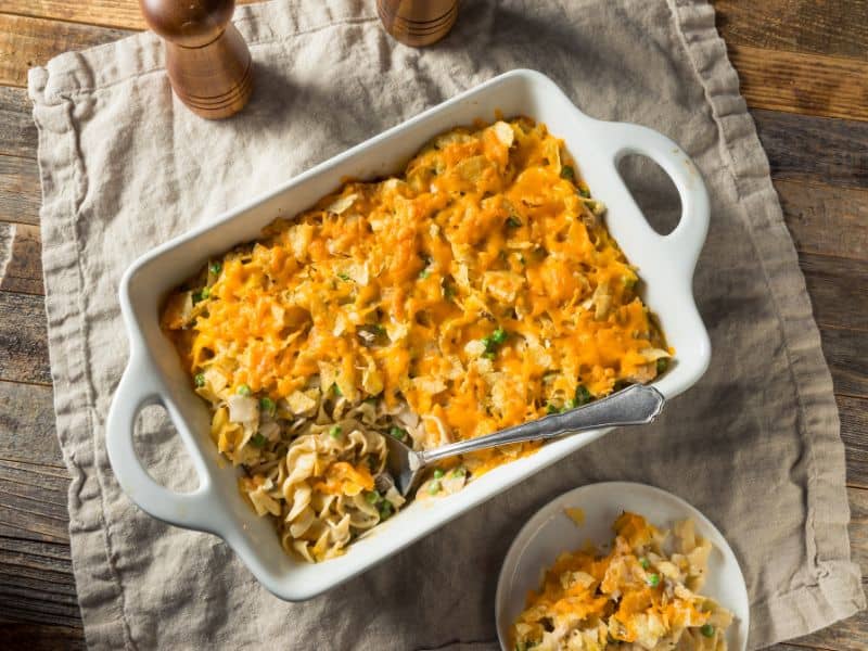 tuna casserole in white casserole dish with some spooned onto a plate