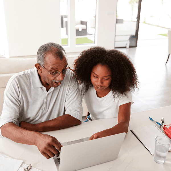 Grandfather and girl using laptop at home.