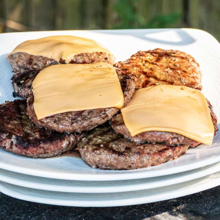 cooked hamburger meat with cheese on some patties