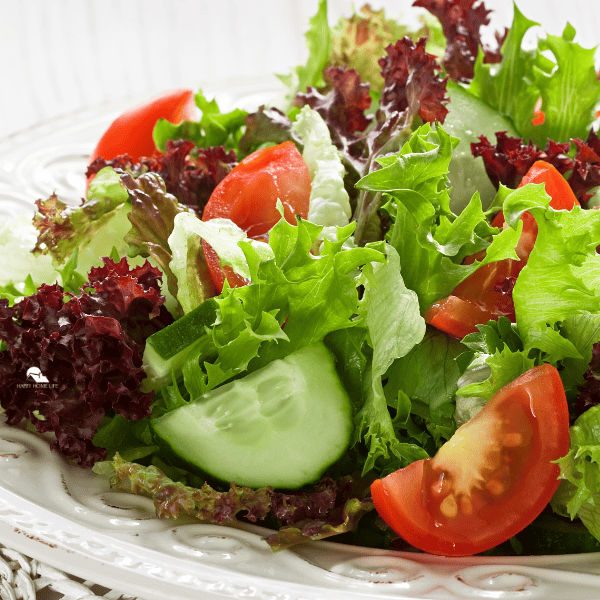 a close up image of fresh salad with greens, tomatoes and other veggies