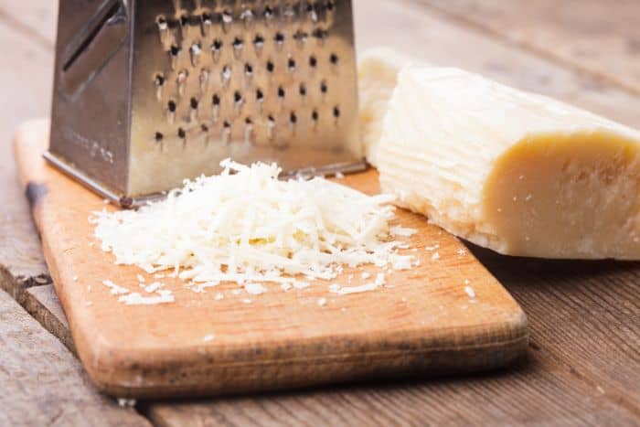 grated parmesan cheese with wooden cutting board and grater