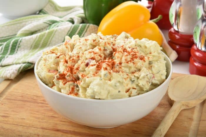 potato salad in white bowl paprika sprinkled on top