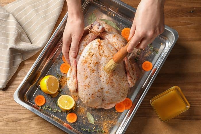 top down view of hands basting a whole turkey