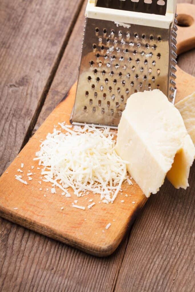 grated aged parmesan on cutting board along with cheese grater