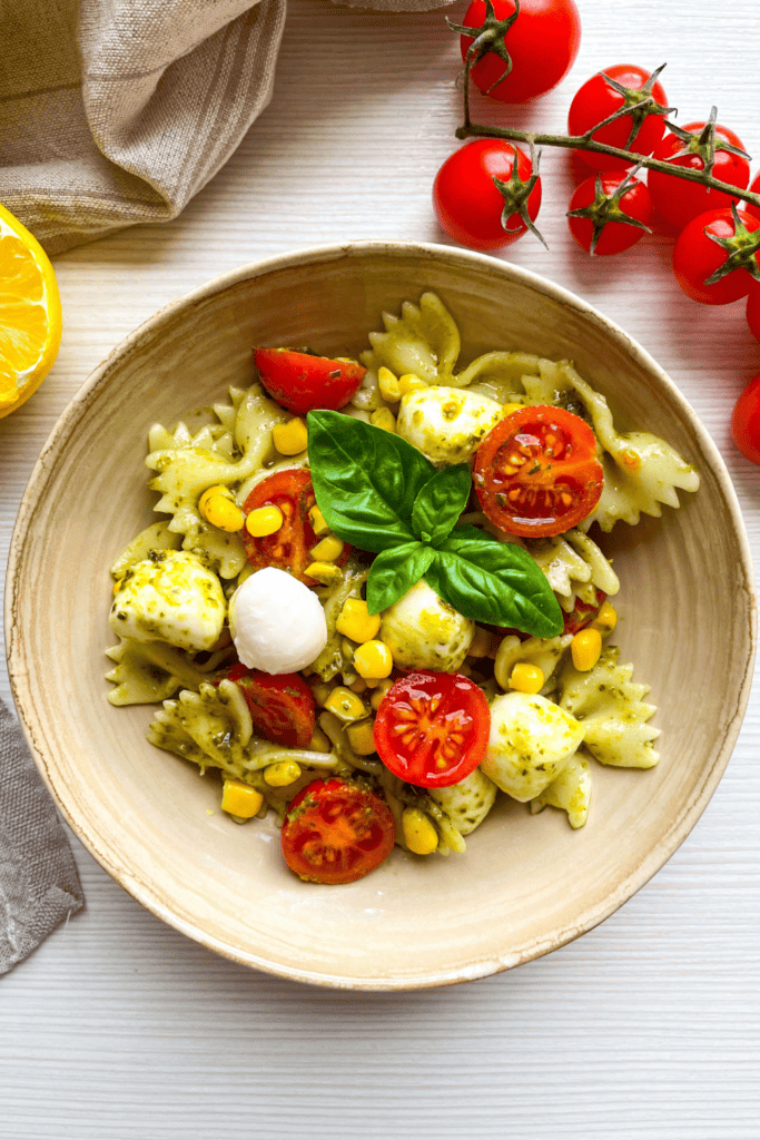 Caprese Bowtie Pasta Salad in a bowl with tomatoes around it