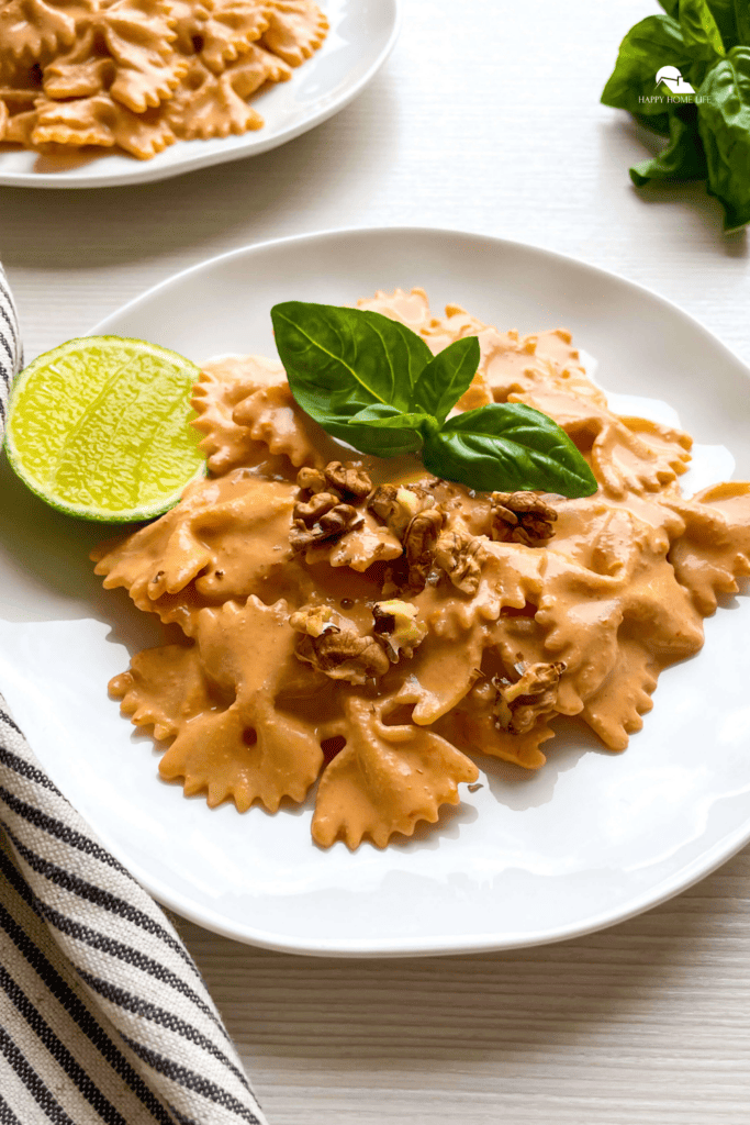 Pasta with Roasted Red Pepper Walnut Sauce in a white plate and pin sized image