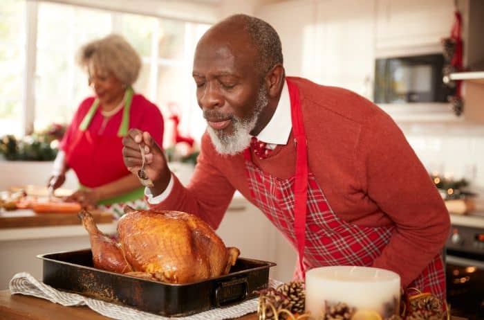 how to baste a turkey - man basting turkey for Christmas