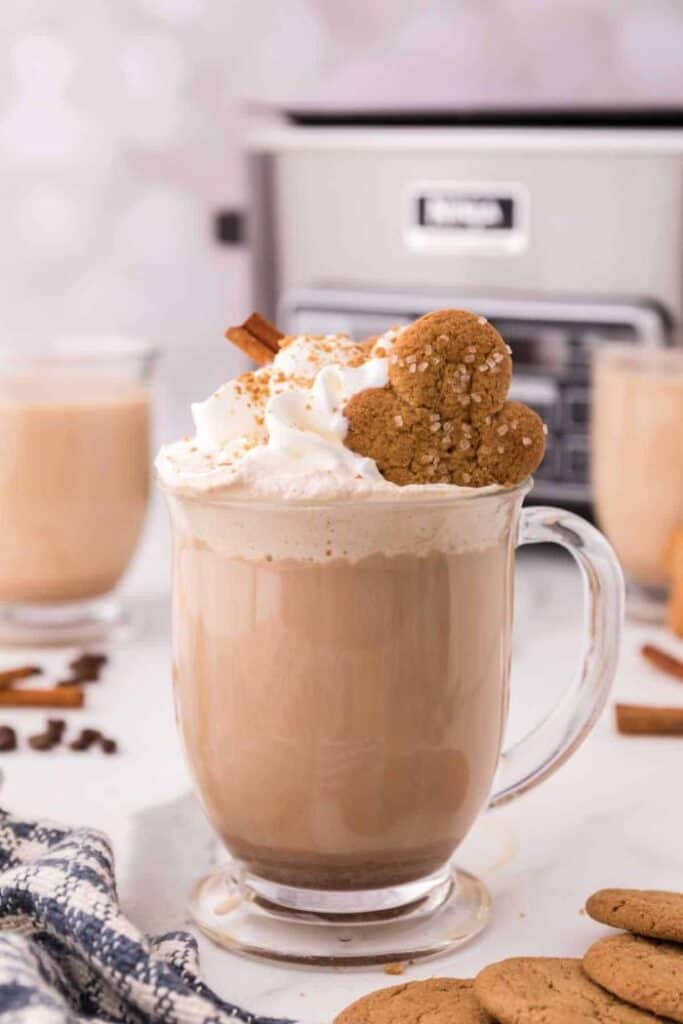 gingerbread latte in clear mug topped with whipped cream and a gingerbread man cookie