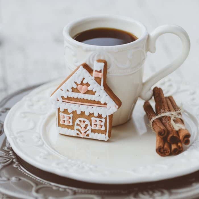 cup of coffee with gingerbread cookie and cinnamon sticks