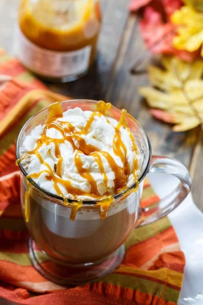 salted caramel latte in clear mug with whipped cream and drizzle of caramel on top