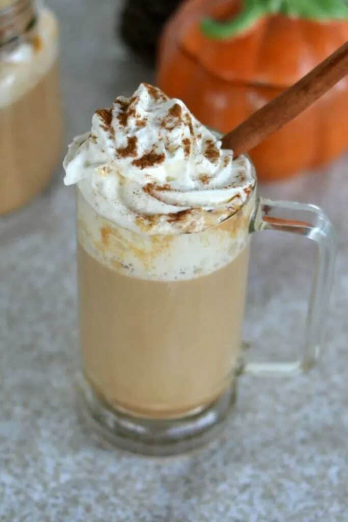 copycat pumpkin spice latte in clear mug with whipped cream and cinnamon