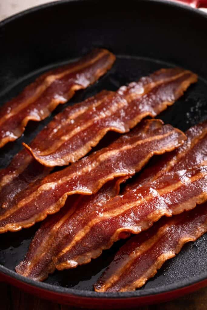 slices of turkey bacon frying in cast iron pan