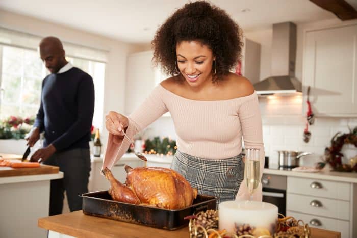 young female basting a turkey for the holidays