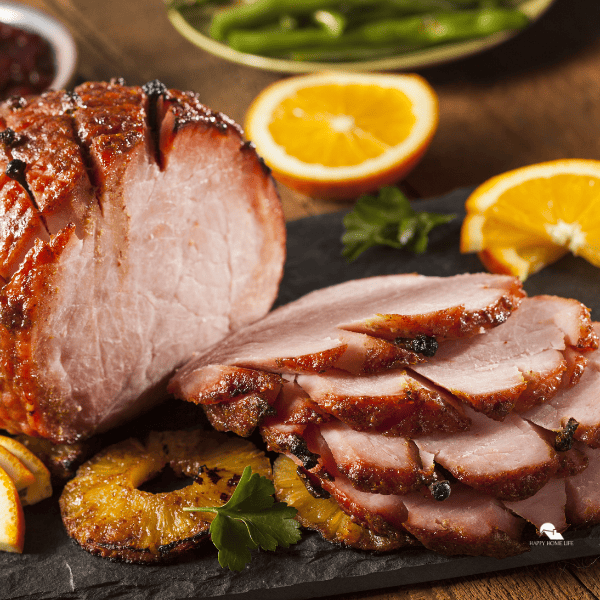 Traditional Sliced Honey Glazed Ham with fruits around it